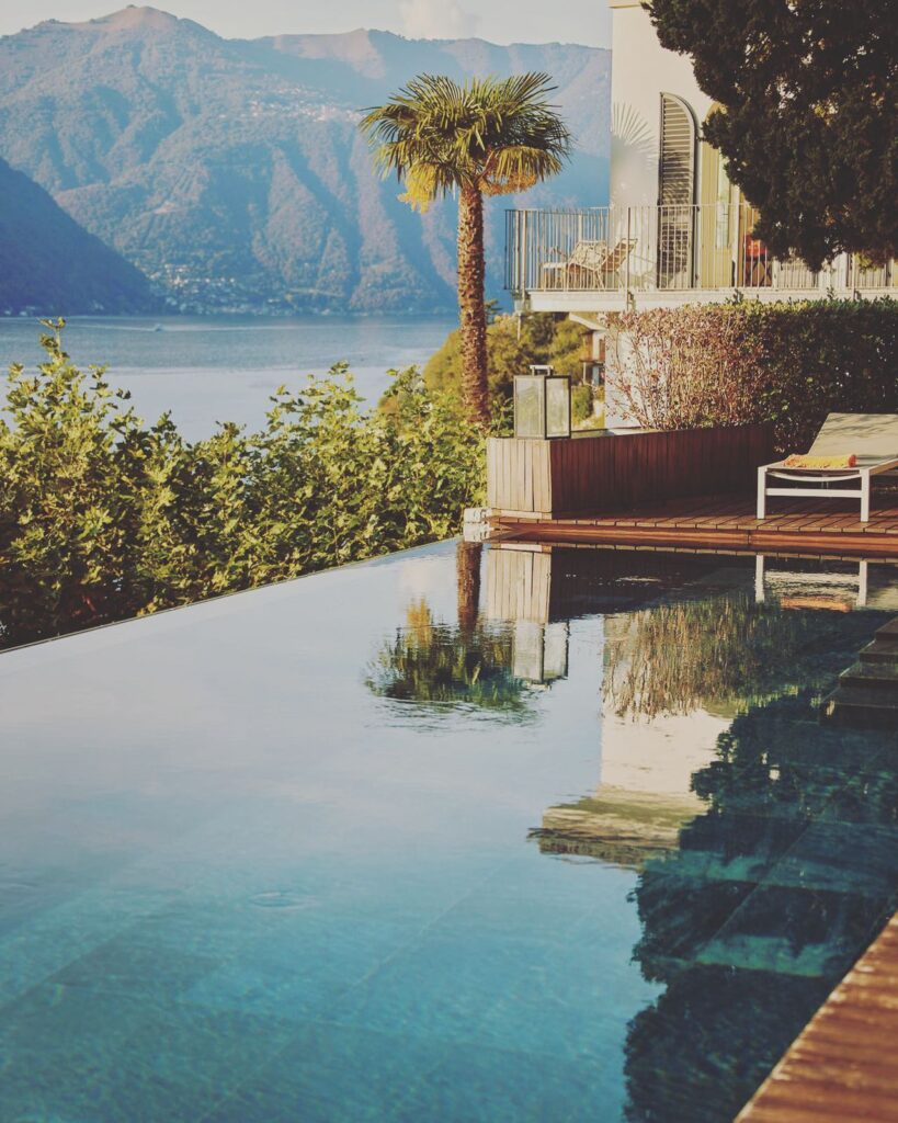 Piscina de borda infinita refletindo palmeira e montanhas no Villa Làrio, hotel boutique entre os hotéis no lago di Como.