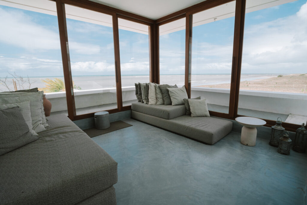 Lounge com grandes janelas de vidro e vista para o mar, conforto e sofisticação em hoteis em são miguel do gostoso.