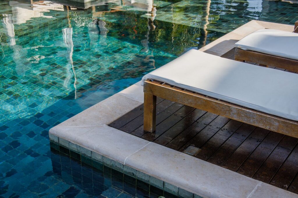 Borda de piscina em pedra e espreguiçadeiras de madeira da Pousada Portofino, destaque entre hoteis em são miguel do gostoso com design contemporâneo.