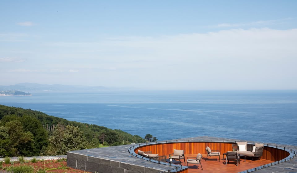Terraço panorâmico com deck circular embutido e vista para o mar no Hotel Akelarre San Sebastian.