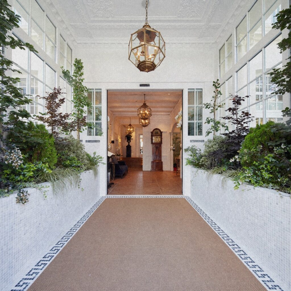 Hall de entrada luminoso do Hotel Villa Favorita San Sebastian com jardins internos e luminárias de latão.