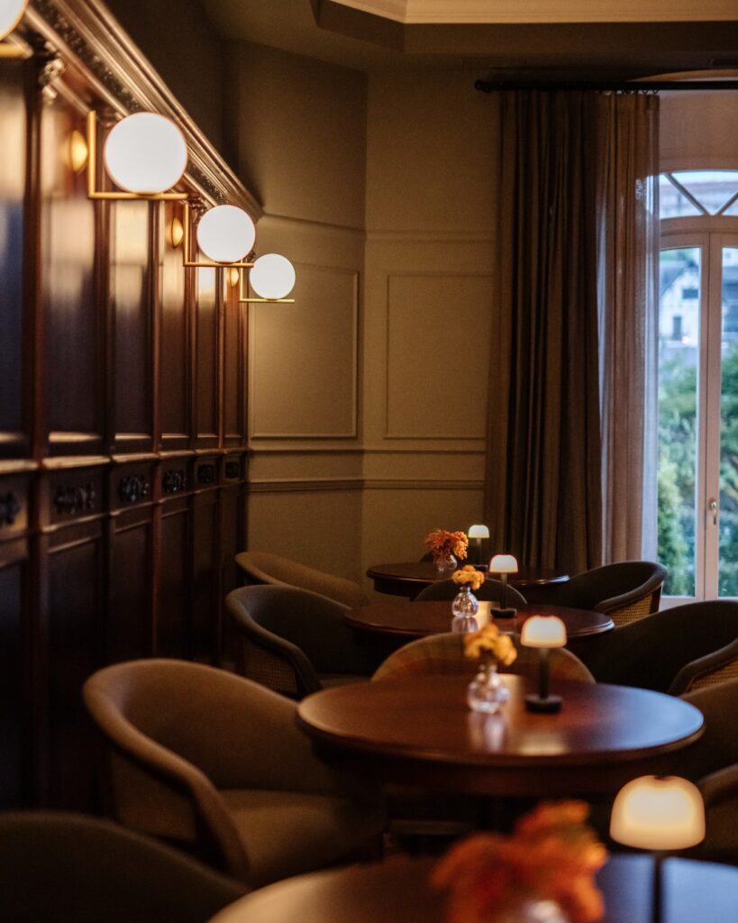 Ambiente de lounge noturno com iluminação suave e painéis de madeira no hotel Villa Soro San Sebastian.