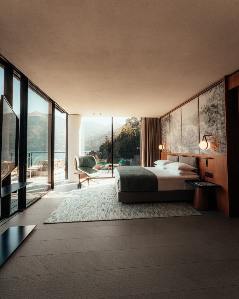 Suíte com vista panorâmica para o lago di Como, cabeceira em madeira e janelas do piso ao teto assinadas por Patricia Urquiola.