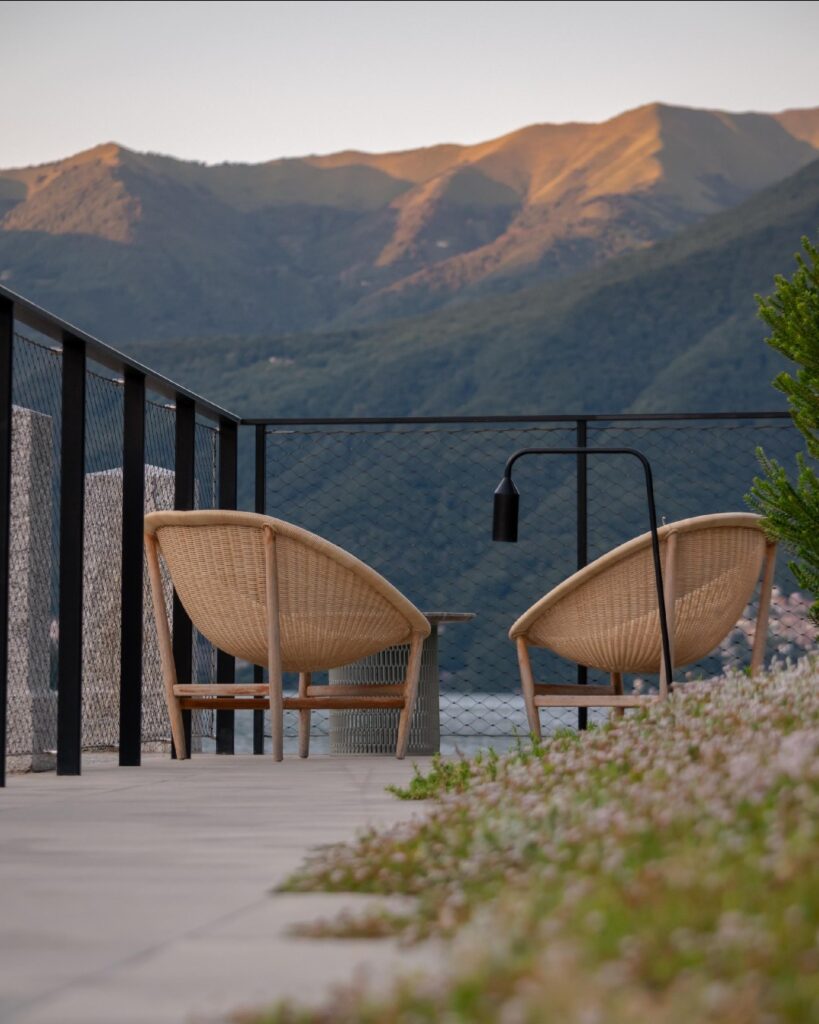 Cadeiras de vime cônico em terraço com vista para as montanhas ao entardecer, nos hotéis no lago di Como de design autoral.