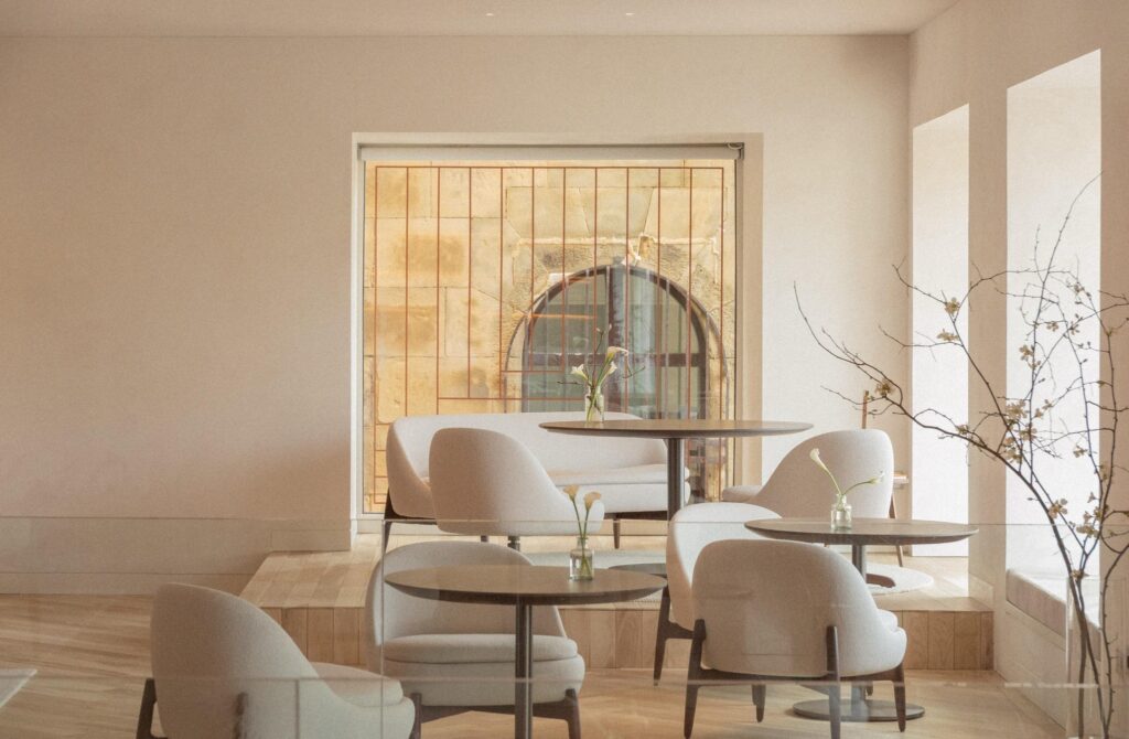 Espaço gastronômico minimalista no Lasala Plaza Hotel San Sebastian com poltronas curvas e vista para arquitetura histórica em pedra.