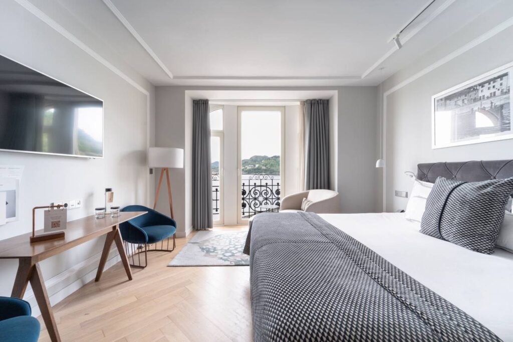 Quarto contemporâneo e luminoso no Lasala Plaza Hotel San Sebastian, com integração visual para a sacada e vista para o mar.