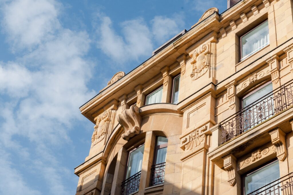 Detalhes arquitetônicos da fachada do Lasala Plaza Hotel San Sebastian, exibindo ornamentos esculpidos em pedra e sacadas clássicas.