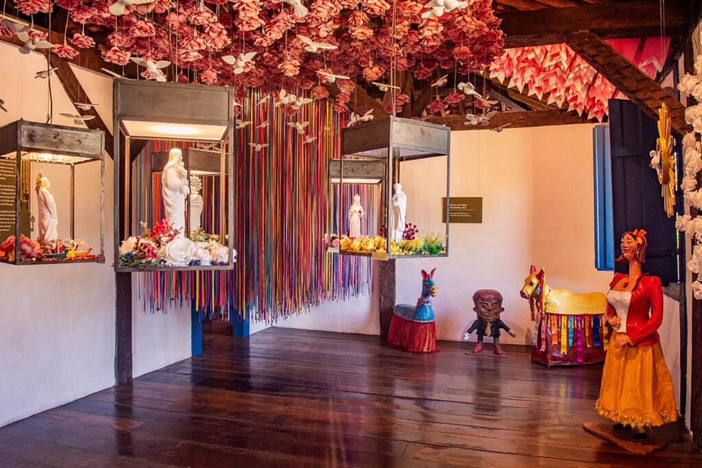 Espaço de arte popular e cultura brasileira na Pousada Literária com decoração colorida suspensa.