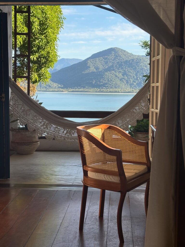 Cadeira de palhinha e rede na varanda com vista para o mar, detalhe do refúgio para páscoa na Pousada Picinguaba.