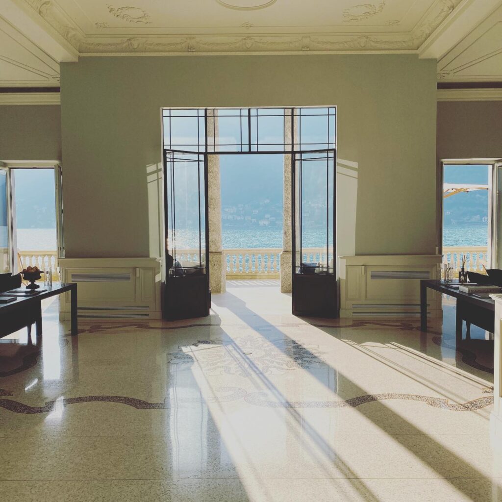 Hall de entrada com piso de terrazzo histórico e poltronas barrocas em veludo verde no Villa Làrio, hotel de design no lago di Como.