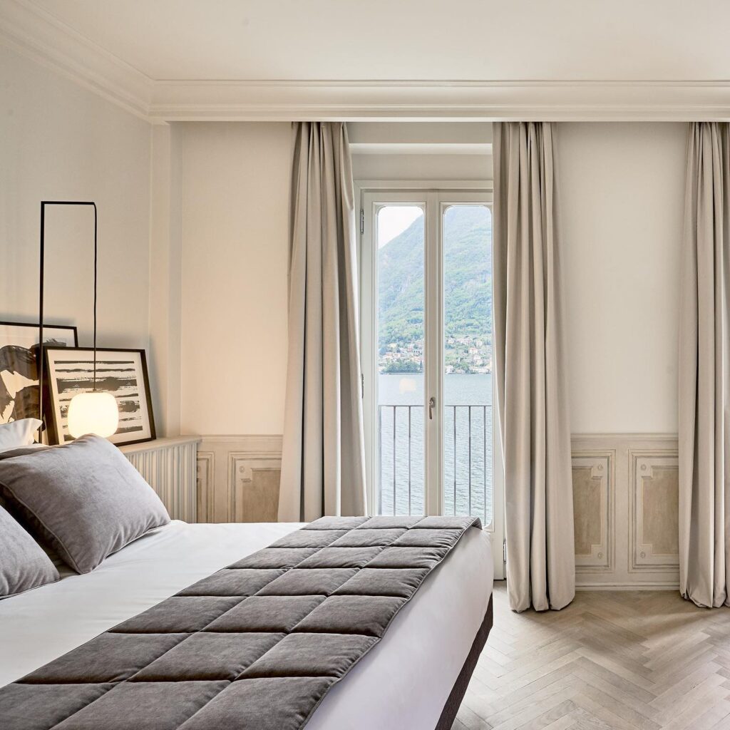 Quarto com lambris brancos, parquet espinha de peixe e vista para o lago, suíte contemporânea nos hotéis no lago di Como.