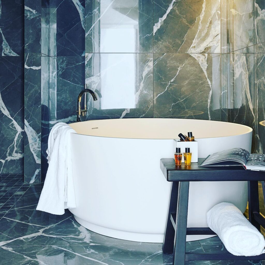 Banheiro em mármore Verde Alpi total com banheira circular branca no Villa Làrio, hotel de design entre os hotéis no lago di Como.