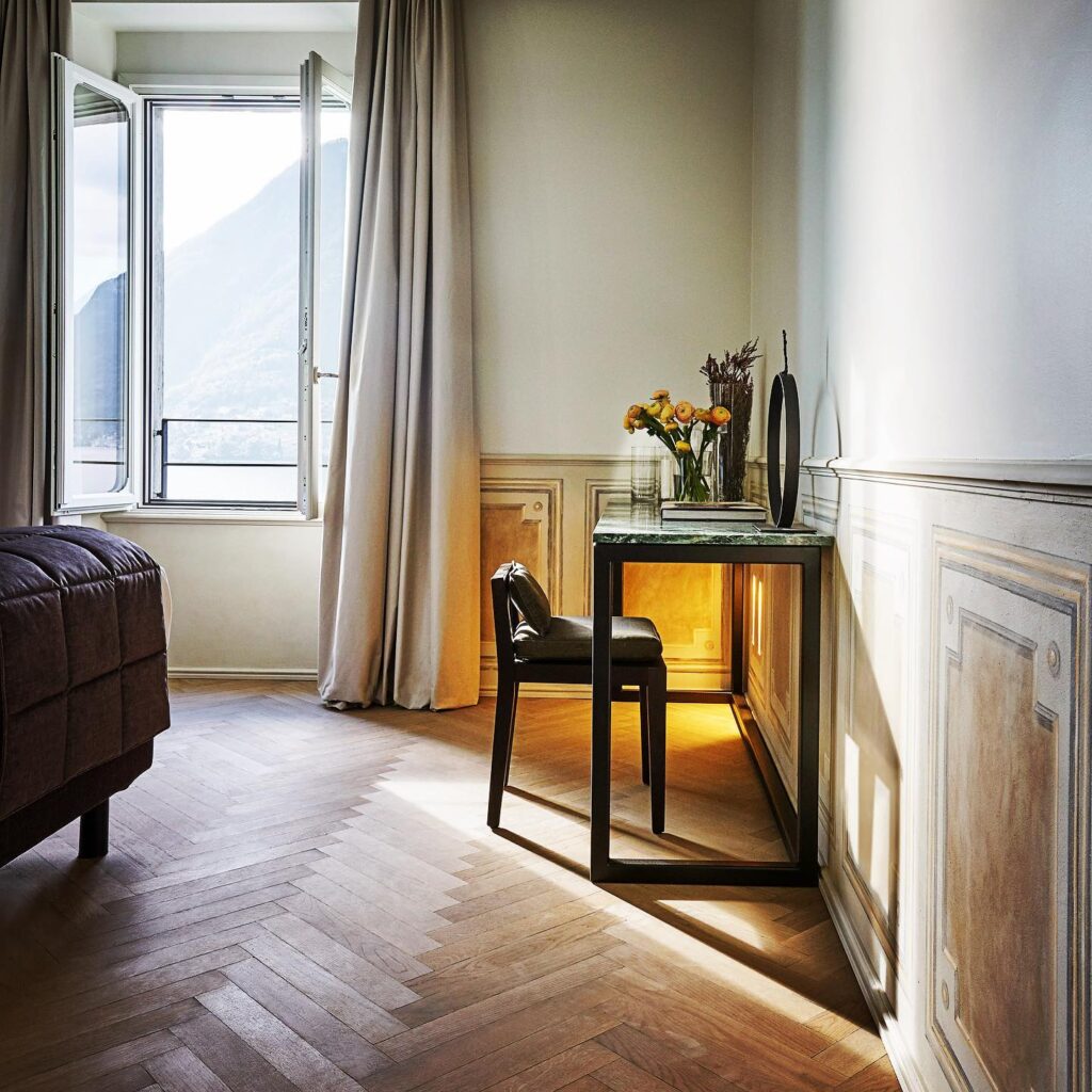 Console de mármore verde e cadeira preta em quarto com parquet espinha de peixe no Villa Làrio, hotel boutique no lago di Como.