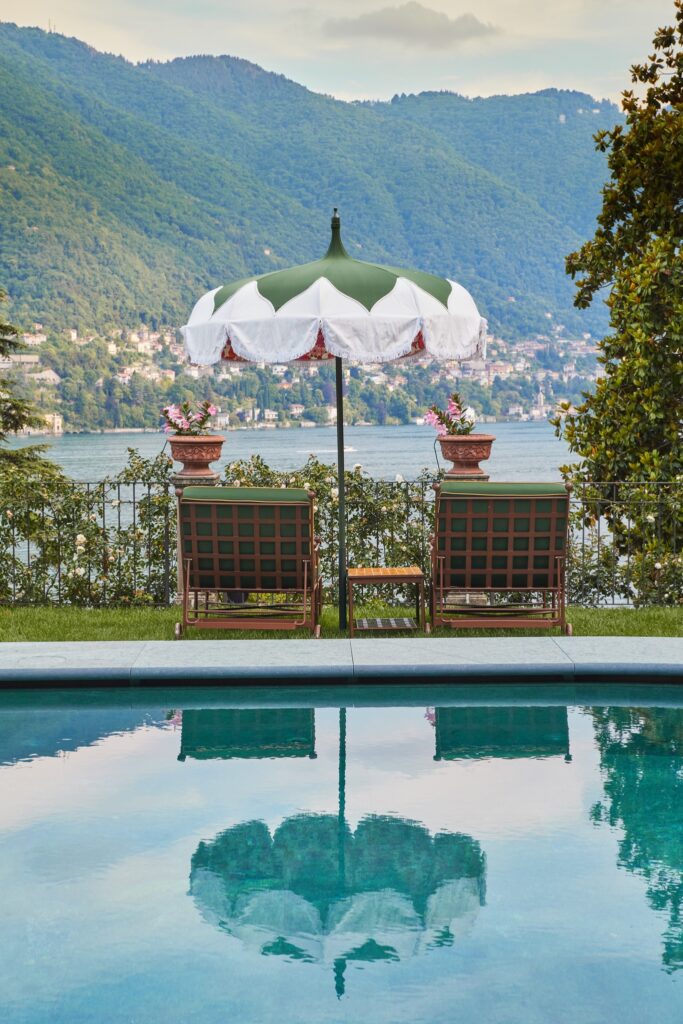 Piscina de borda infinita com guarda-sol vintage e vista para o Lago di Como no Passalacqua, eleito melhor hotel do mundo.