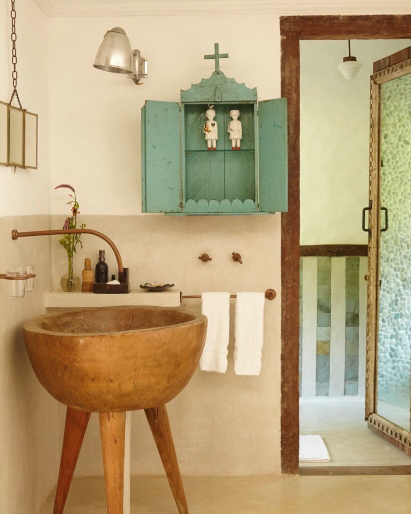 Banheiro com pia de tronco de madeira e armário vintage azul, destacando o design exclusivo deste refúgio para páscoa.