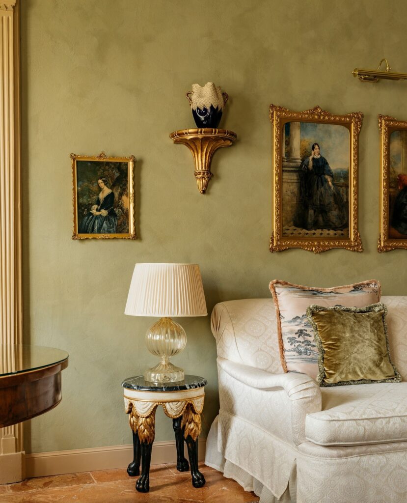 Galeria de retratos históricos e luminária de Murano dourado em sala do Passalacqua, hotel boutique de ultra-luxo no lago di Como.