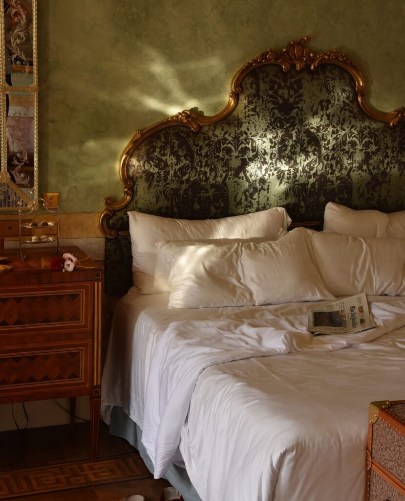 Cabeceira barroca dourada com damasco escuro em quarto do Passalacqua, hospedagem de ultra-luxo entre os hotéis no lago di Como.