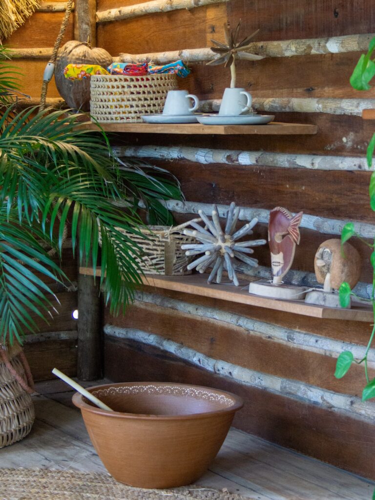 Detalhe de decoração rústica com objetos artesanais e prateleiras de madeira no Rancho do Peixe.