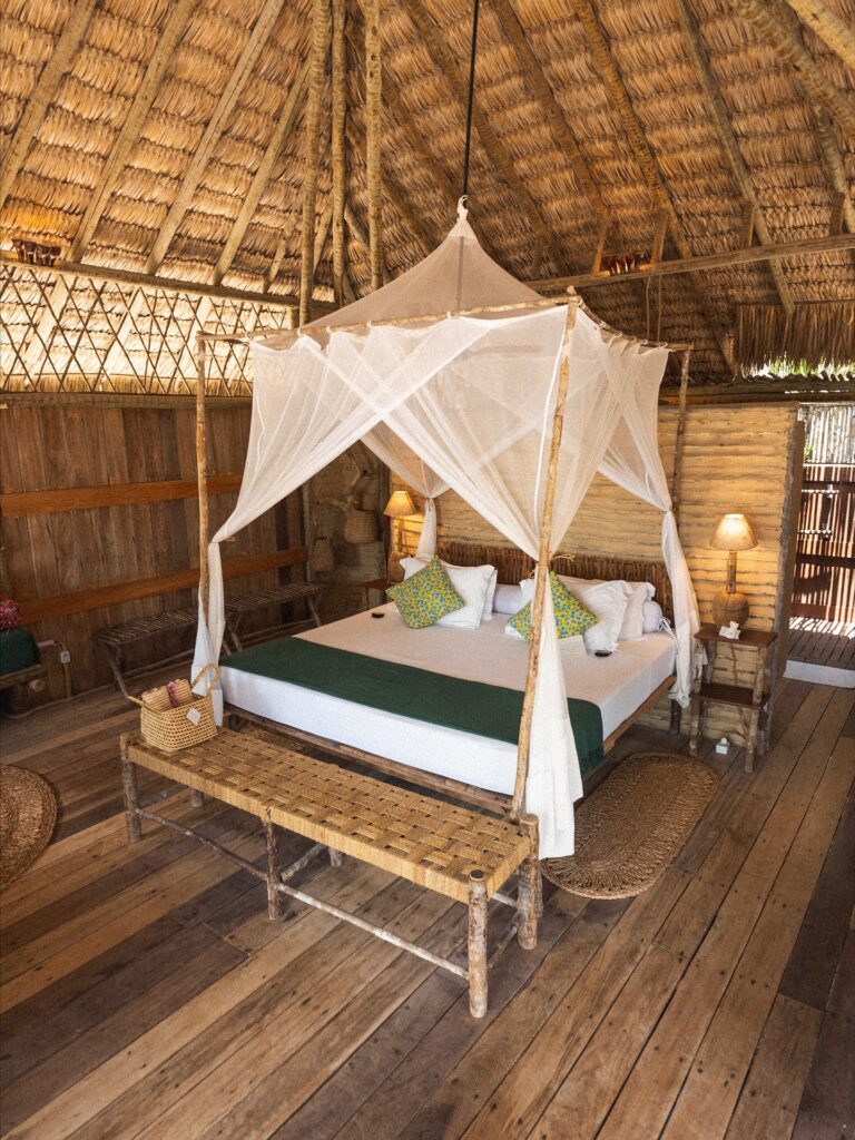 Quarto amplo com teto alto de palha, cama king size e decoração em fibras naturais no Rancho do Peixe.