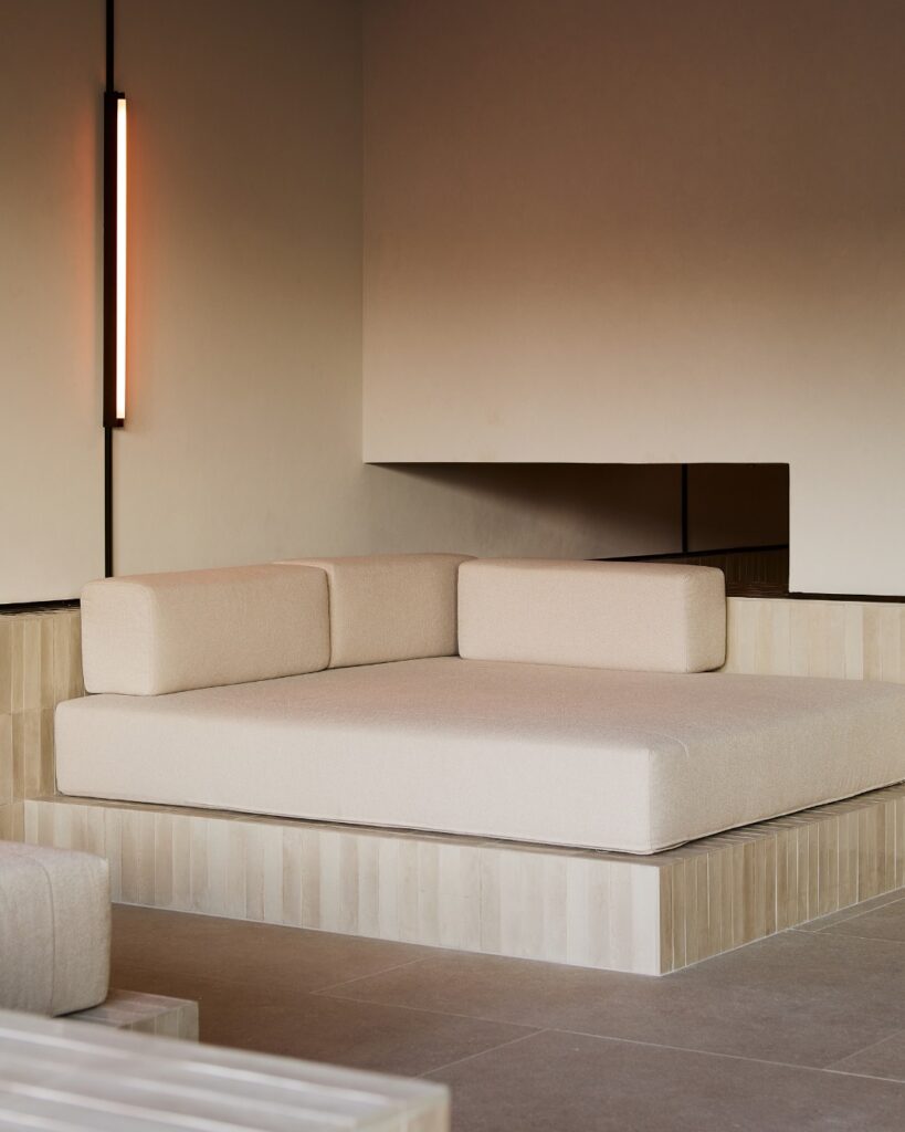 Daybed de bouclé sobre plataforma de travertino ripado, área de descanso do spa no The Lake Como EDITION, hotel de design no lago di Como.