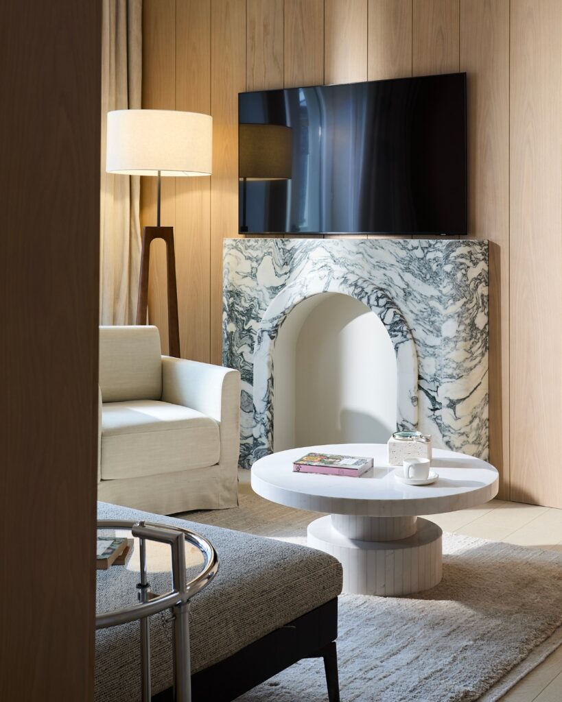 Lareira escultórica em mármore Calacatta Turquoise com abertura arqueada em living de suíte no The Lake Como EDITION.