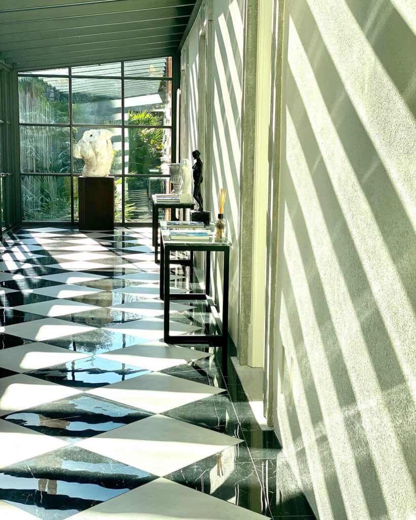 Corredor com piso de mármore em xadrez diagonal e luz criando listras de sombra, interior do Villa Làrio nos hotéis no lago di Como.