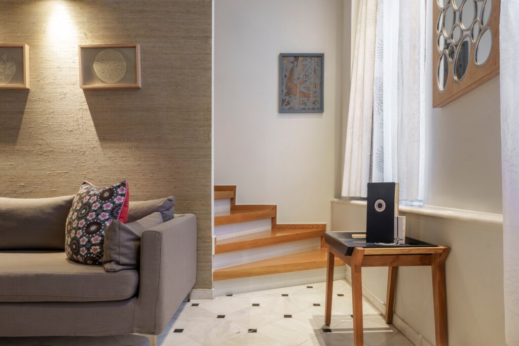 Interior sofisticado do Casa Delfino, um dos melhores hoteis da ilha de creta, com parede texturizada, sofá cinza e piso de mármore clássico.