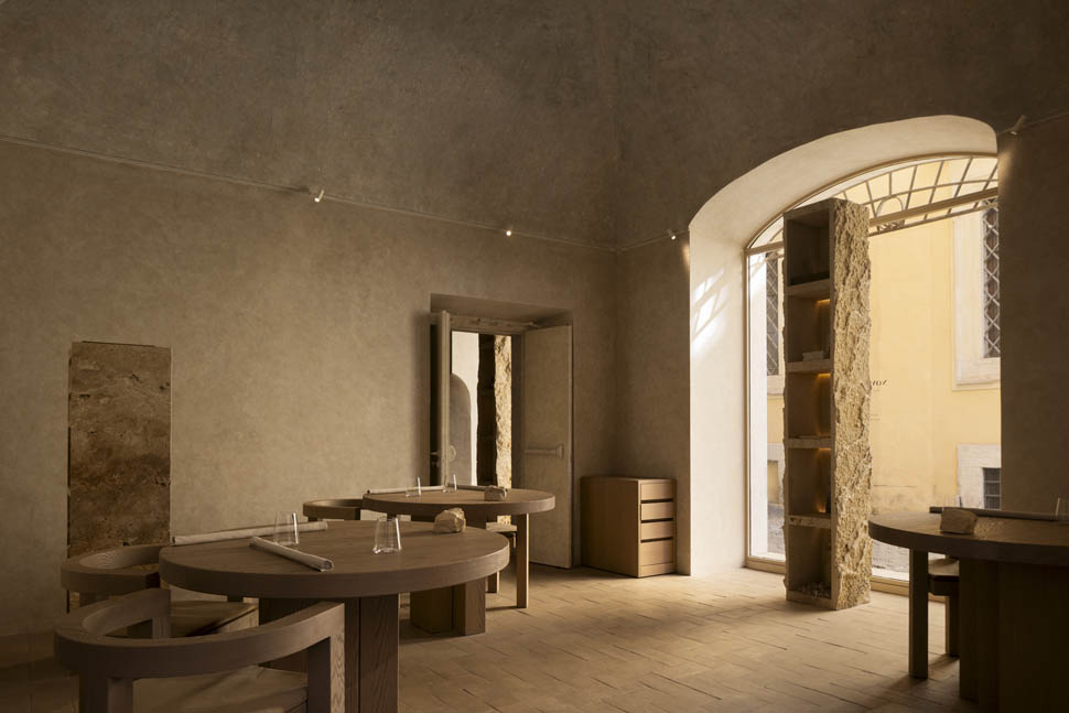 Salão principal do restaurante nomos ante com teto abobadado, mesas de madeira e iluminação pontual.