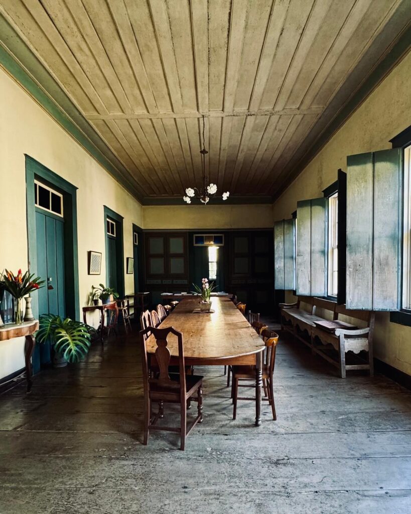 Sala de jantar colonial com mesa de madeira maciça e teto em saia e camisa em arquitetura colonial brasileira preservada.
