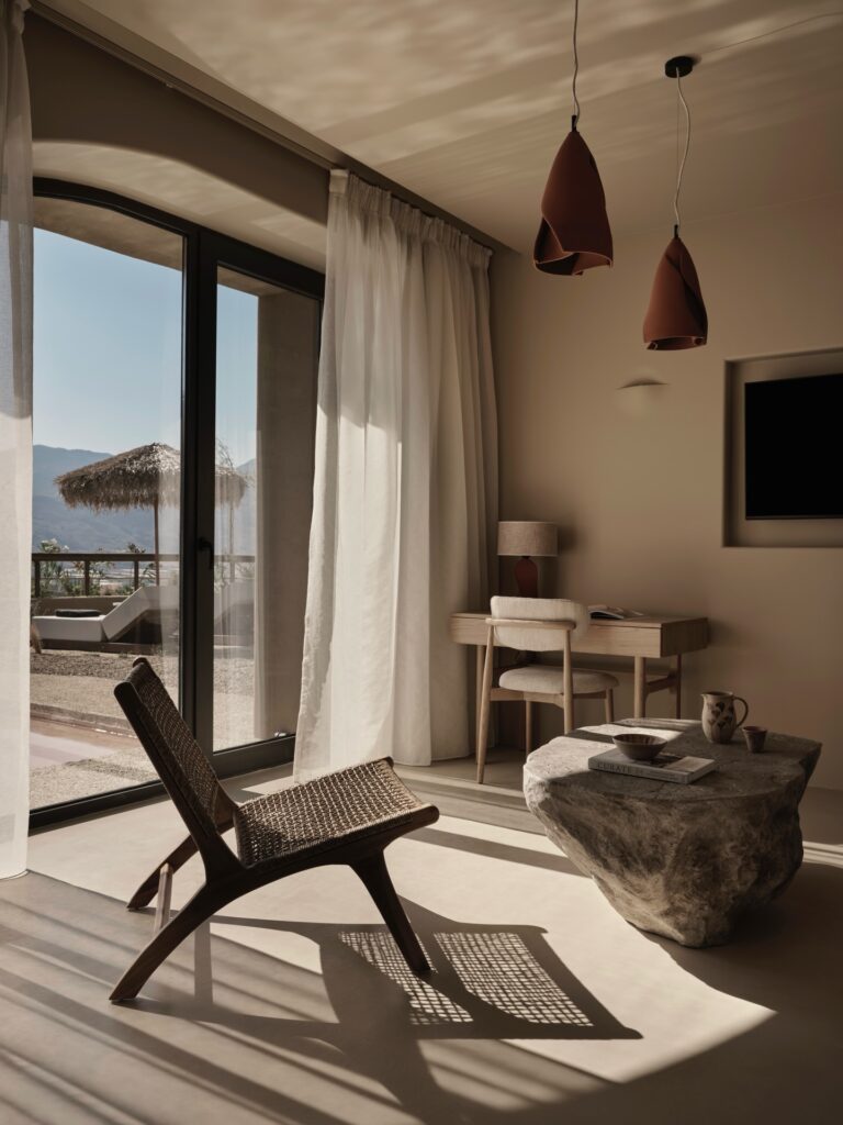 Design de interiores minimalista com mesa de pedra e tons terrosos no Tella Thera, entre os melhores hoteis da ilha de creta.