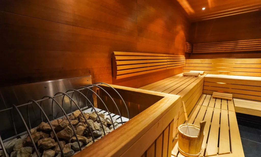 Interior de sauna moderna revestida em madeira clara, ideal para relaxamento em uma viagem de bem estar com foco em detox e saúde.