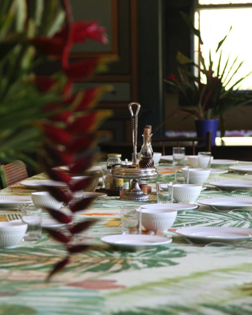 Detalhe de mesa posta com estamparia botânica e louças brancas em turismo histórico no Vale do Paraíba.