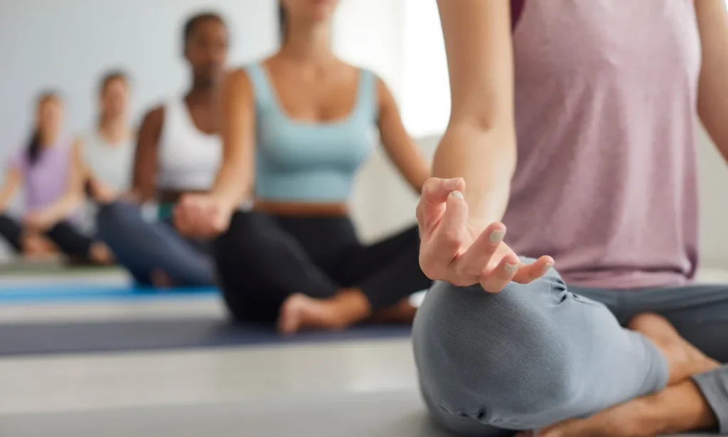 Grupo praticando meditação em ambiente iluminado, destacando atividades de espiritualidade em uma viagem de bem estar.
