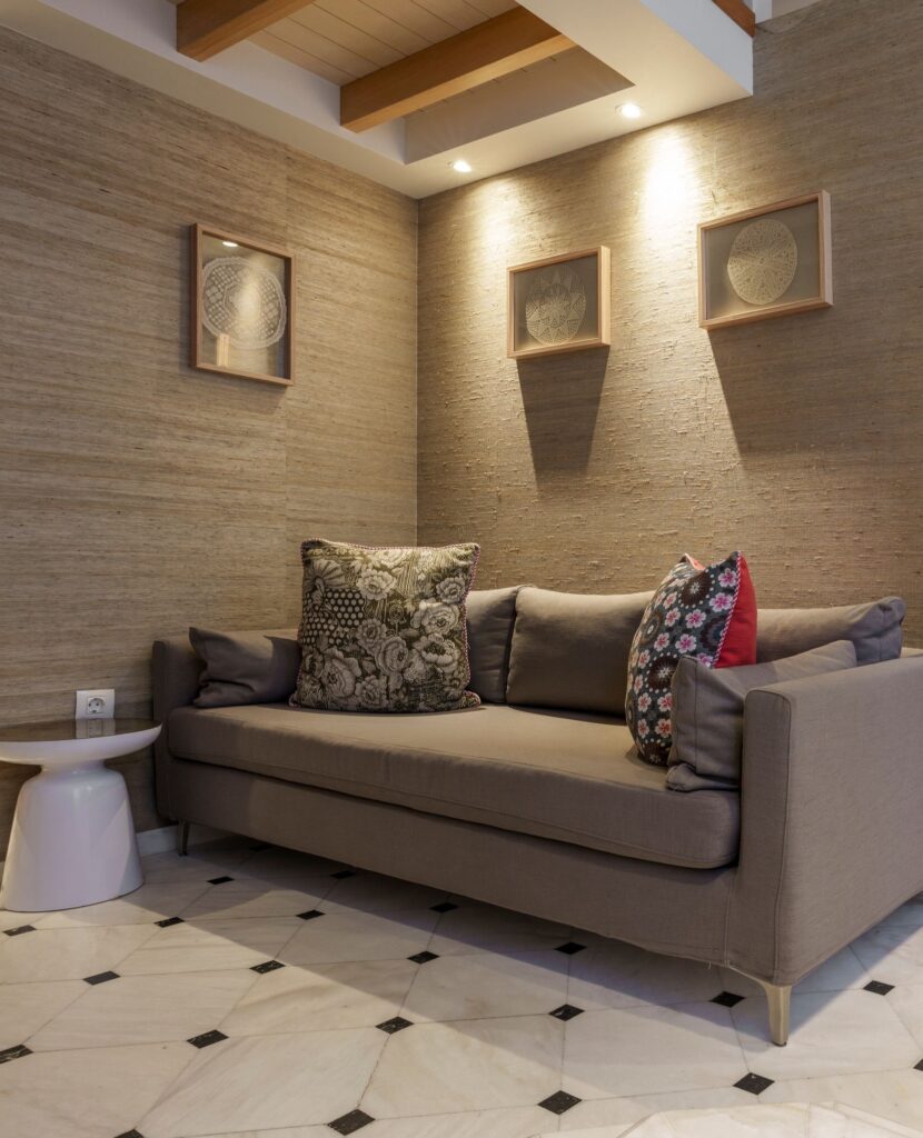 Lounge aconchegante com sofá cinza e iluminação focada no Casa Delfino, referência em melhores hoteis da ilha de creta.