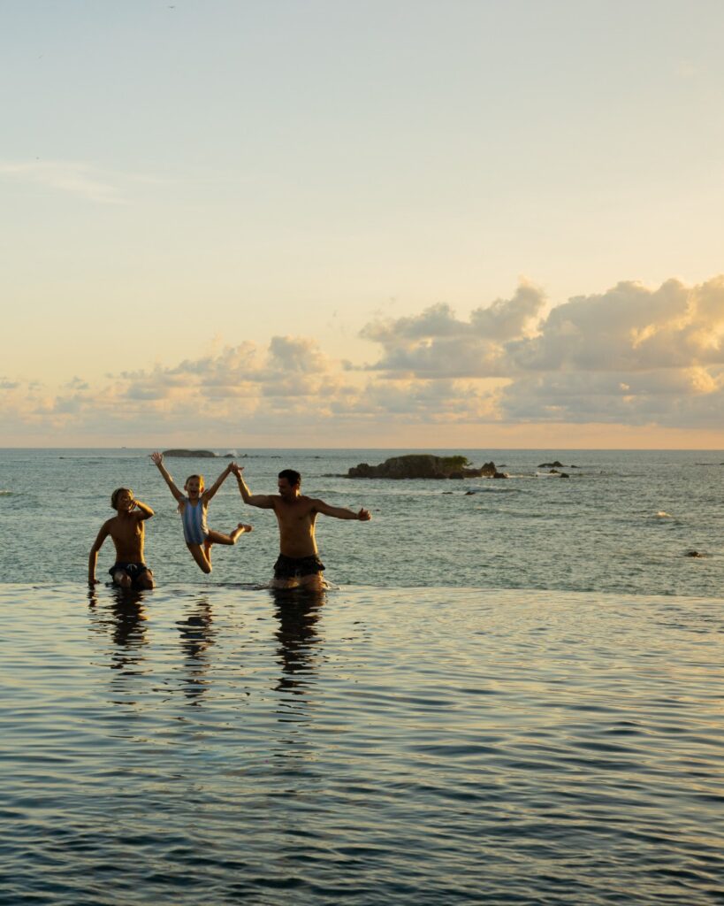 Piscina de borda infinita com vista para o oceano em resort de luxo, destino perfeito para viagem de bem estar em família.