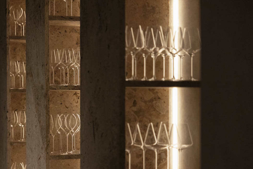 Detalhe de prateleiras de pedra retroiluminadas com taças no restaurante nomos ante.