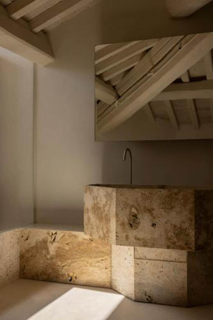 Lavabo com cuba de pedra esculpida e teto de madeira no restaurante nomos ante.