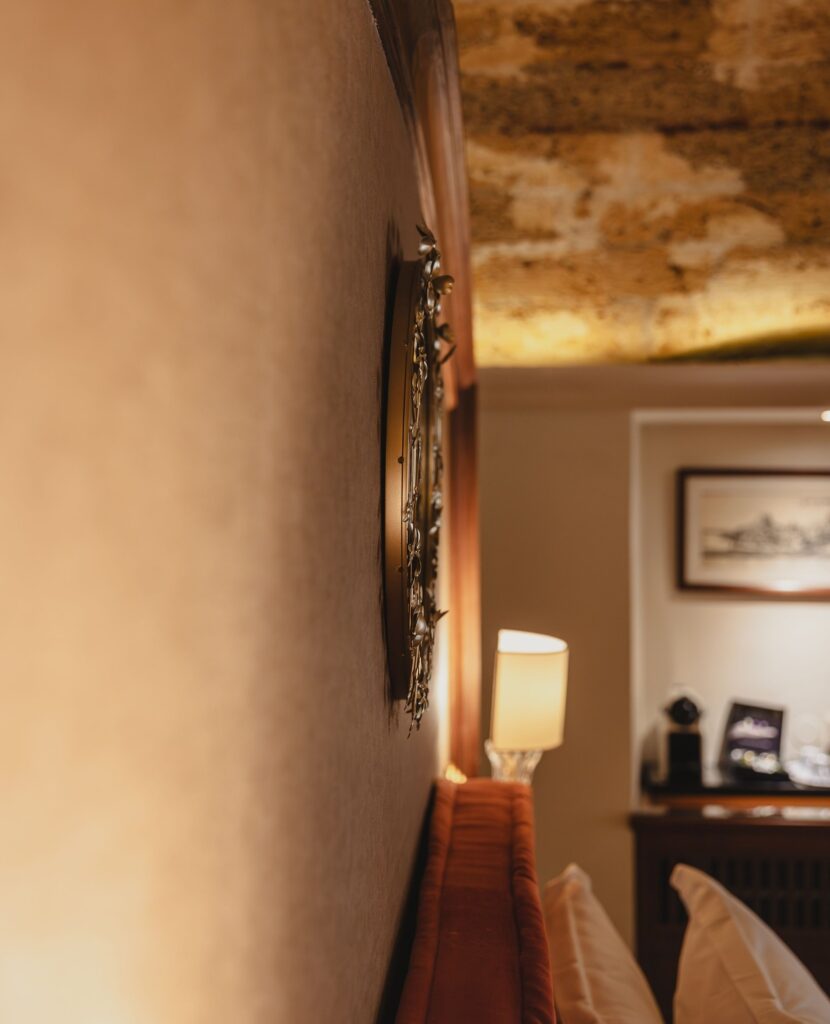 Detalhe decorativo com parede de pedra e iluminação suave no Casa Delfino, entre os melhores hoteis da ilha de creta.