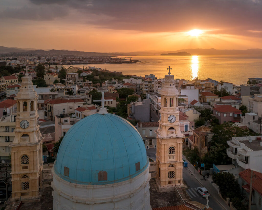 Pôr do sol sobre Chania na Ilha de Creta, com destaque para a cúpula azul da igreja e arquitetura histórica veneziana.