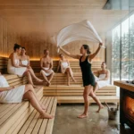 Ritual de Aufguss em sauna panorâmica com vista para floresta, experiência exclusiva em viagem de bem estar na neve.