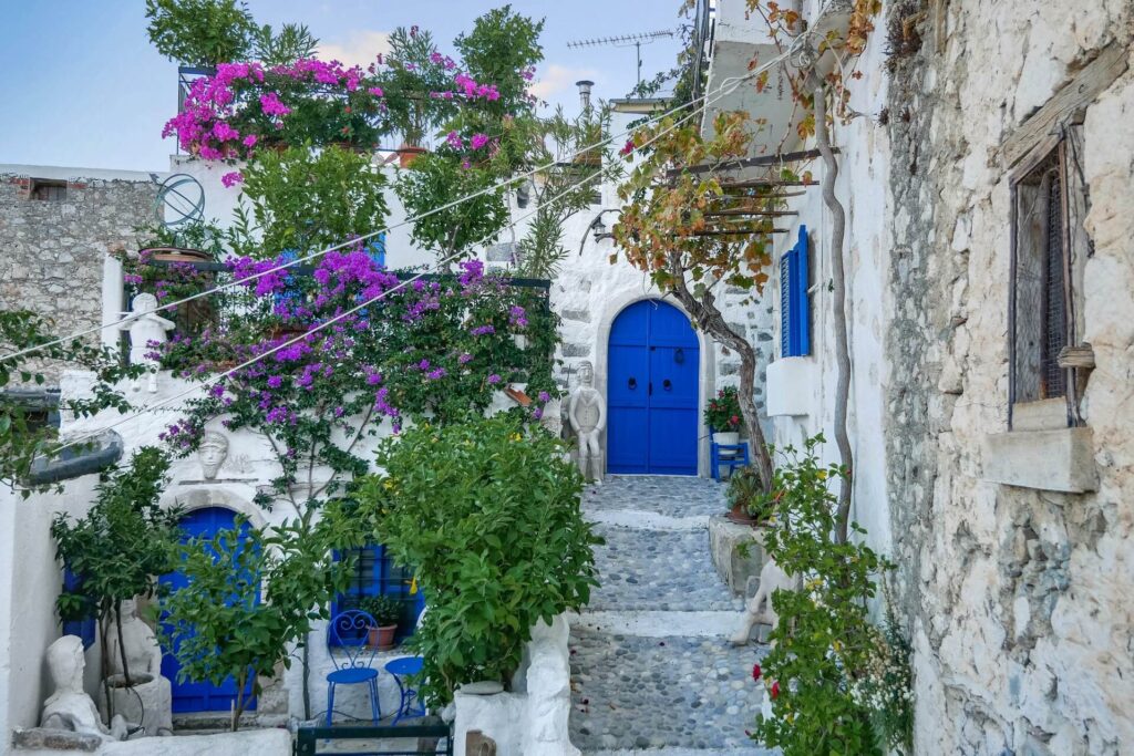 Rua típica em Kritsa na Ilha de Creta, apresentando casas brancas, portas azuis e flores de bougainvillea.
