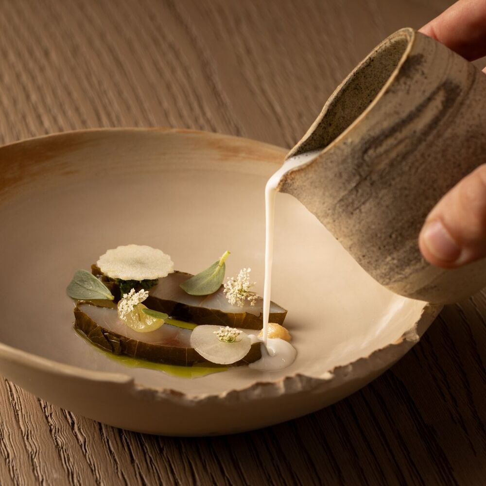 Detalhe de prato gourmet servido em louça artesanal no restaurante nomos ante.