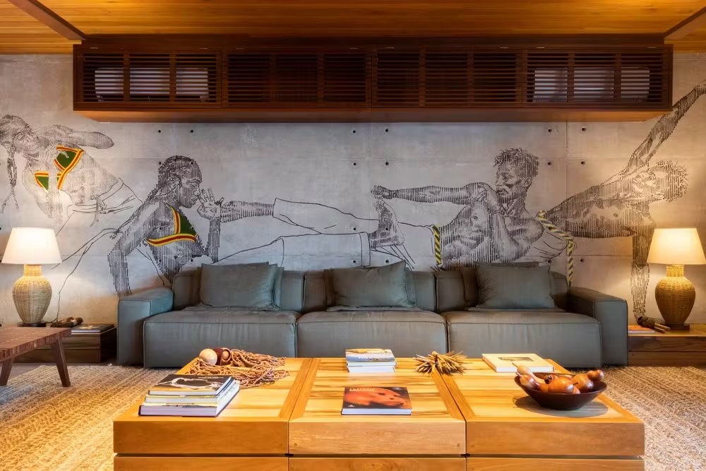 Decoração de sala com parede de concreto e arte urbana em casa de luxo para alugar em Itacaré, focando no mobiliário de design contemporâneo.