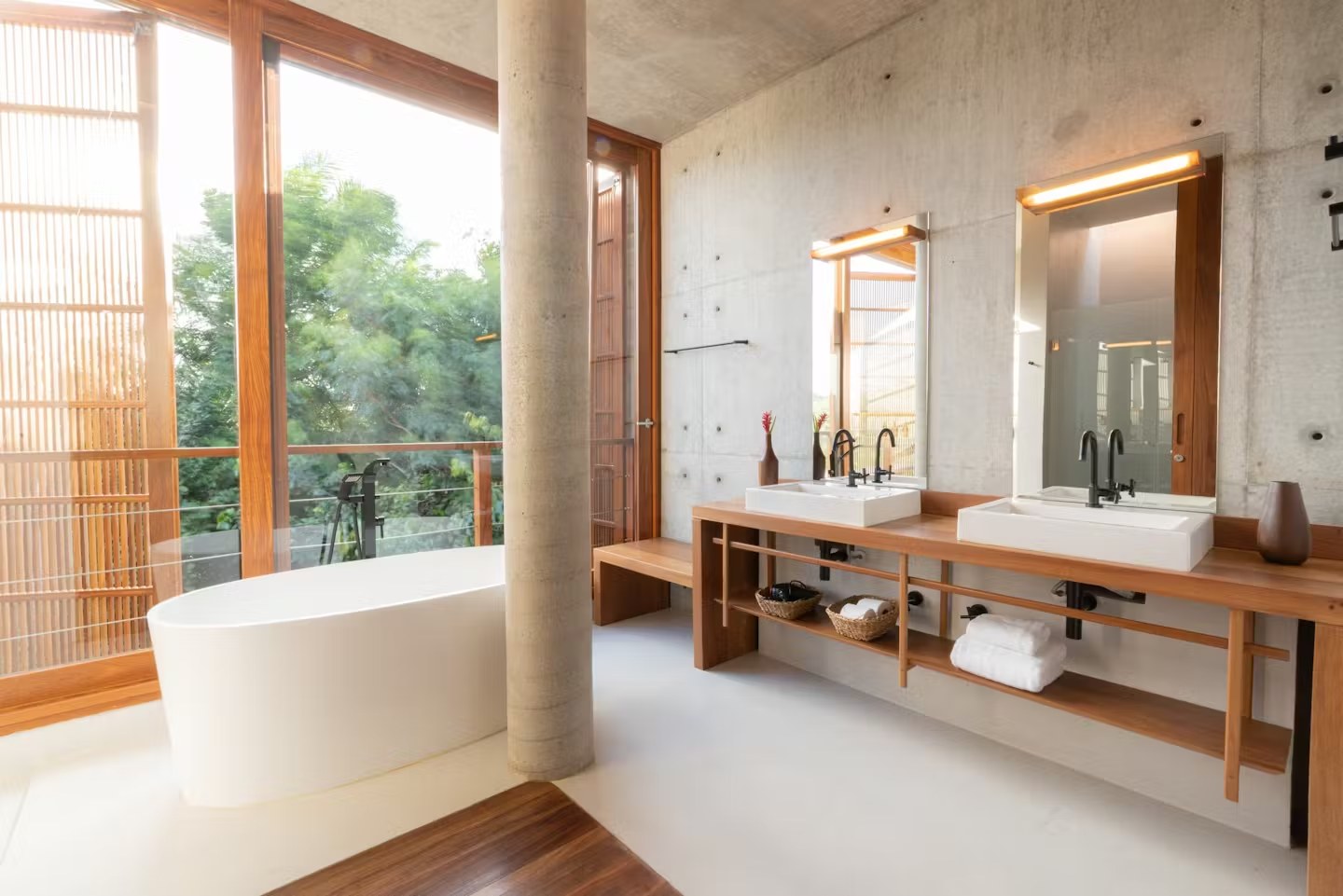 Banheiro de luxo com banheira e bancada de madeira em casa de luxo para alugar em Itacaré, com vista para a natureza e iluminação zenital.