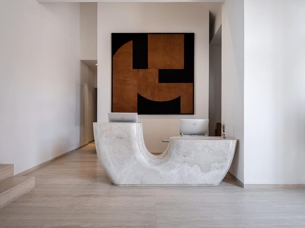 Recepção minimalista com balcão de pedra esculpida, detalhe de design sofisticado nos melhores hoteis da ilha de creta.