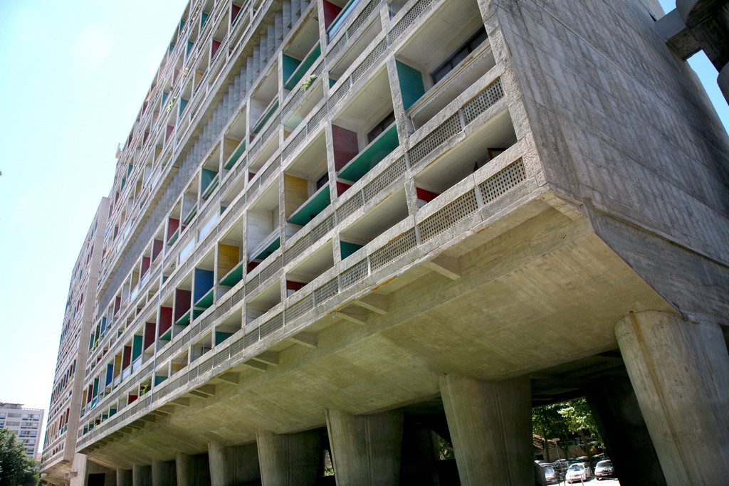 Vista dos pilotis e fachada colorida da Unité d'Habitation de Le Corbusier, sintetizando os princípios da arquitetura modernista funcional.