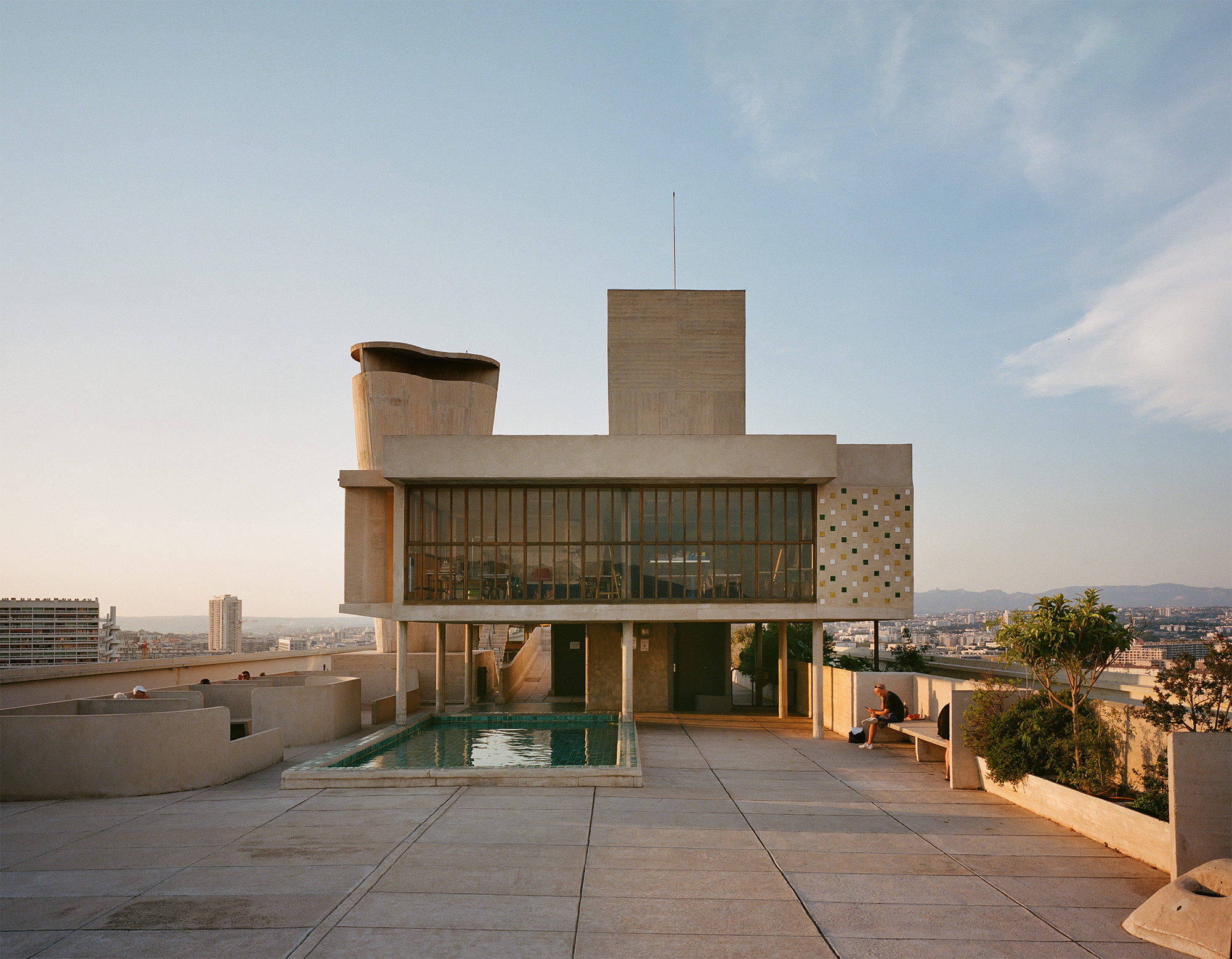 Terraço-jardim da Unité d'Habitation em Marselha, com esculturas de concreto e piscina, pilares da funcionalidade na arquitetura modernista.