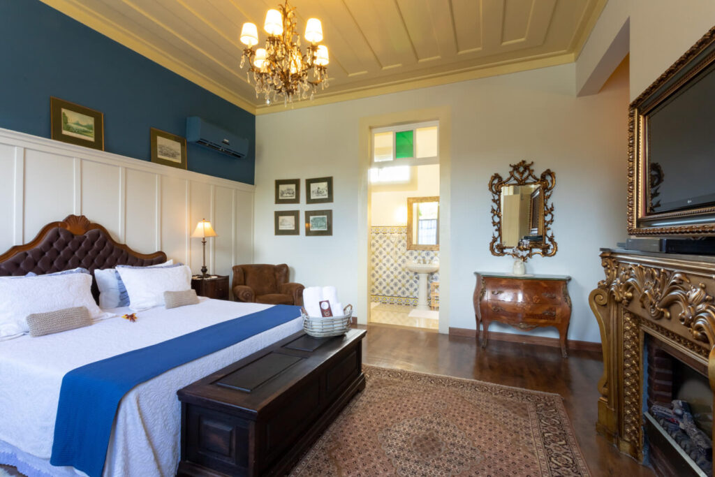 Suíte de luxo com parede azul e lareira clássica na Fazenda União, uma das melhores fazendas históricas para se hospedar.