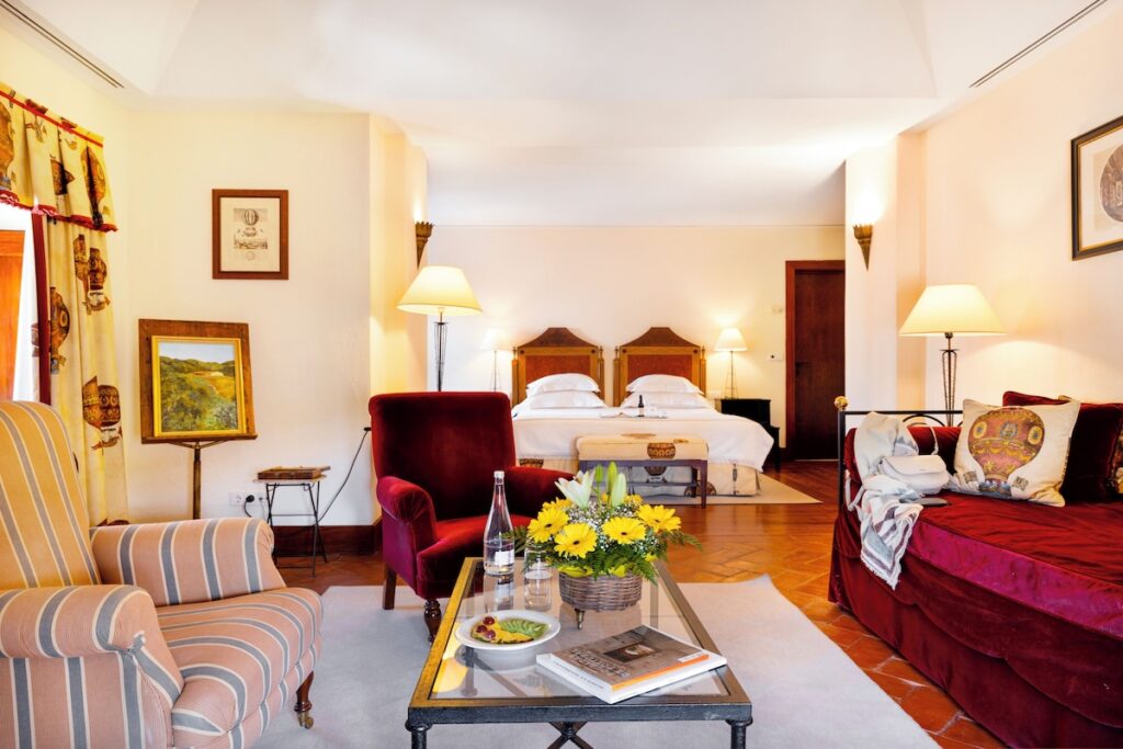 Quarto clássico com tons de bordô e mobiliário histórico em uma das pousadas em portugal.