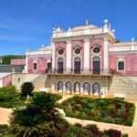 Fachada de pal&aacute;cio rosa com jardins franceses, exemplo de arquitetura luxuosa em pousadas em portugal.